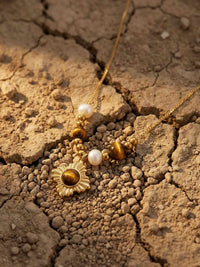 Golden Sun Kette auf getrockneter Erde – Nemomatheo Tigerauge-Halskette mit goldenem Sonnenanhänger Flatlay