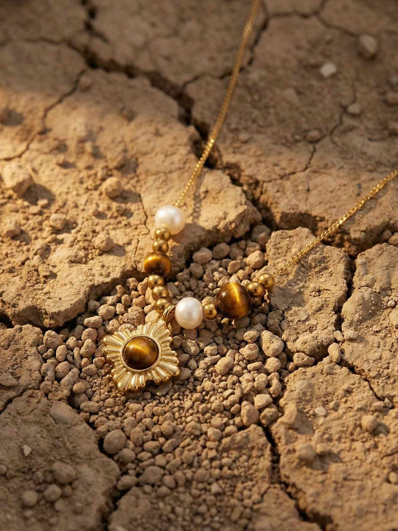 Golden Sun Kette auf getrockneter Erde – Nemomatheo Tigerauge-Halskette mit goldenem Sonnenanhänger Flatlay