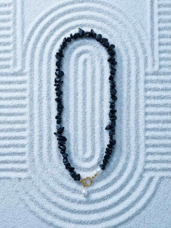 Nemomatheo Midnight Pearl Kette auf Zen-Sandhintergrund – Elegante Obsidian-Perlenkette Flatlay