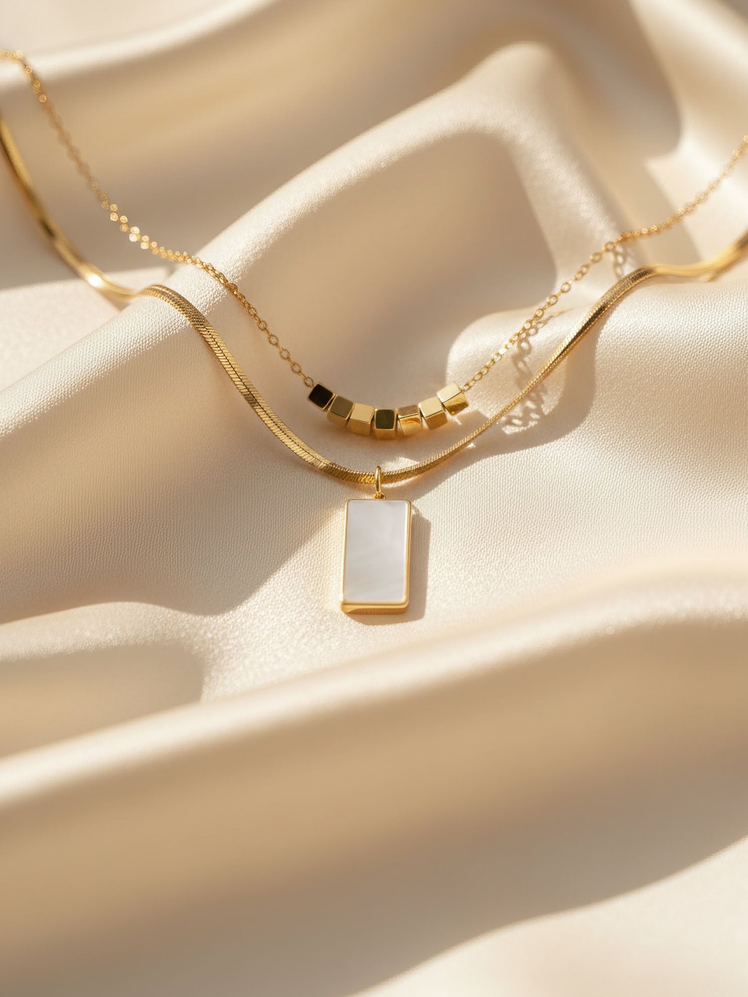 Kette Urban Mirror im Sonnenlicht – vergoldete Layering-Halskette mit Perlmutt auf cremefarbener Seide