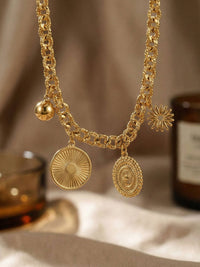 Lucky Charms Armband Handansicht – goldene Muenze, Sonne und Amulett-Charms am Handgelenk