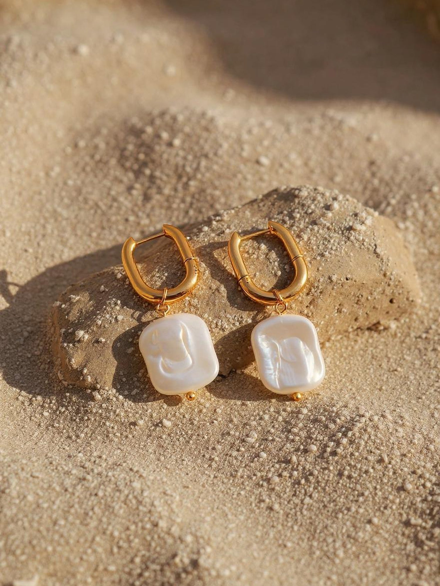 Marea Ohrringe Detailansicht – goldene Perlenohrringe auf Sand mit maritimem Flair