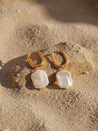 Marea Ohrringe Detailansicht – goldene Perlenohrringe auf Sand mit maritimem Flair