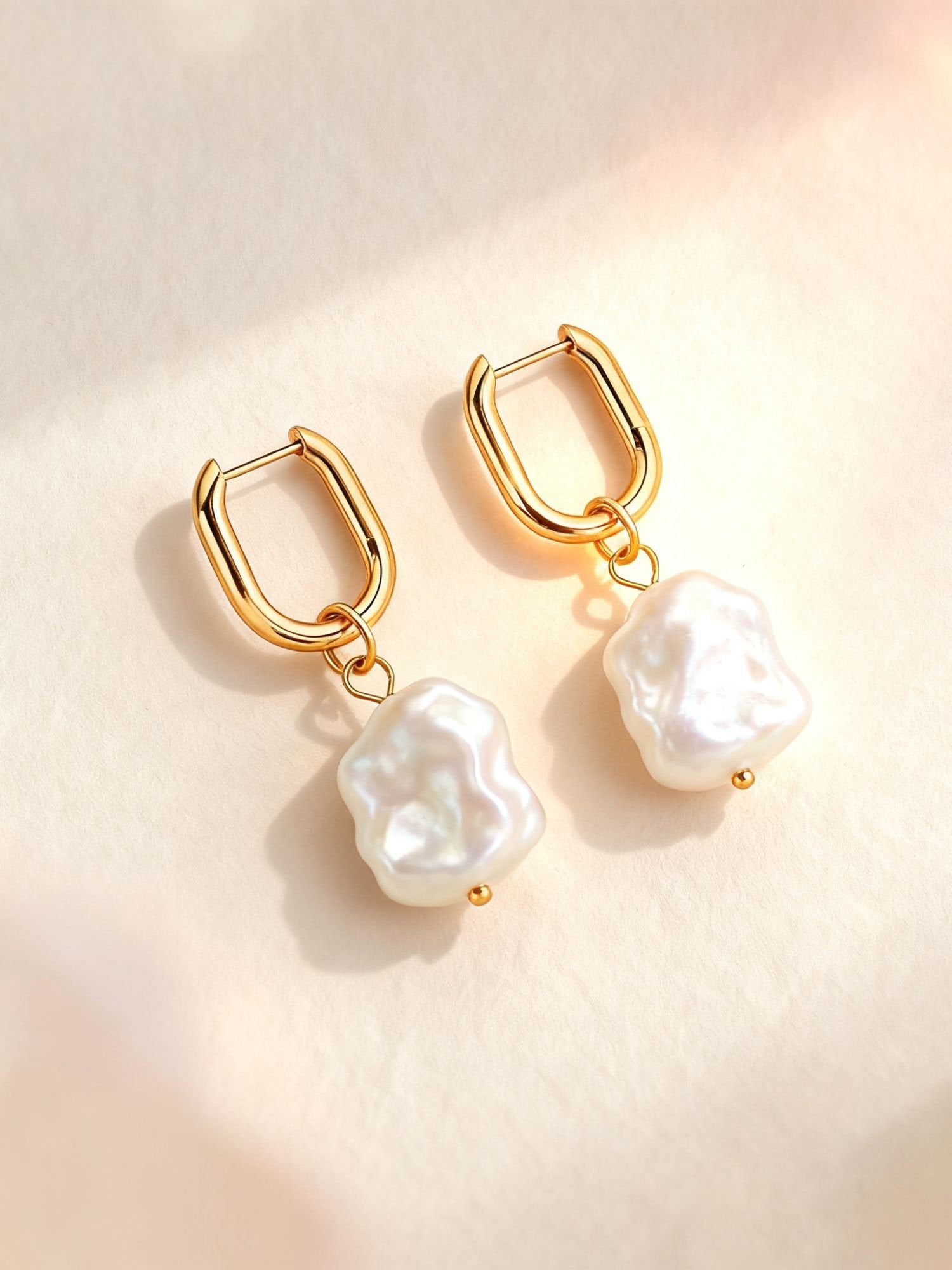 Marea Ohrringe Produktfoto – goldene Huggie Hoops mit barocken Süßwasserperlen auf hellem Hintergrund