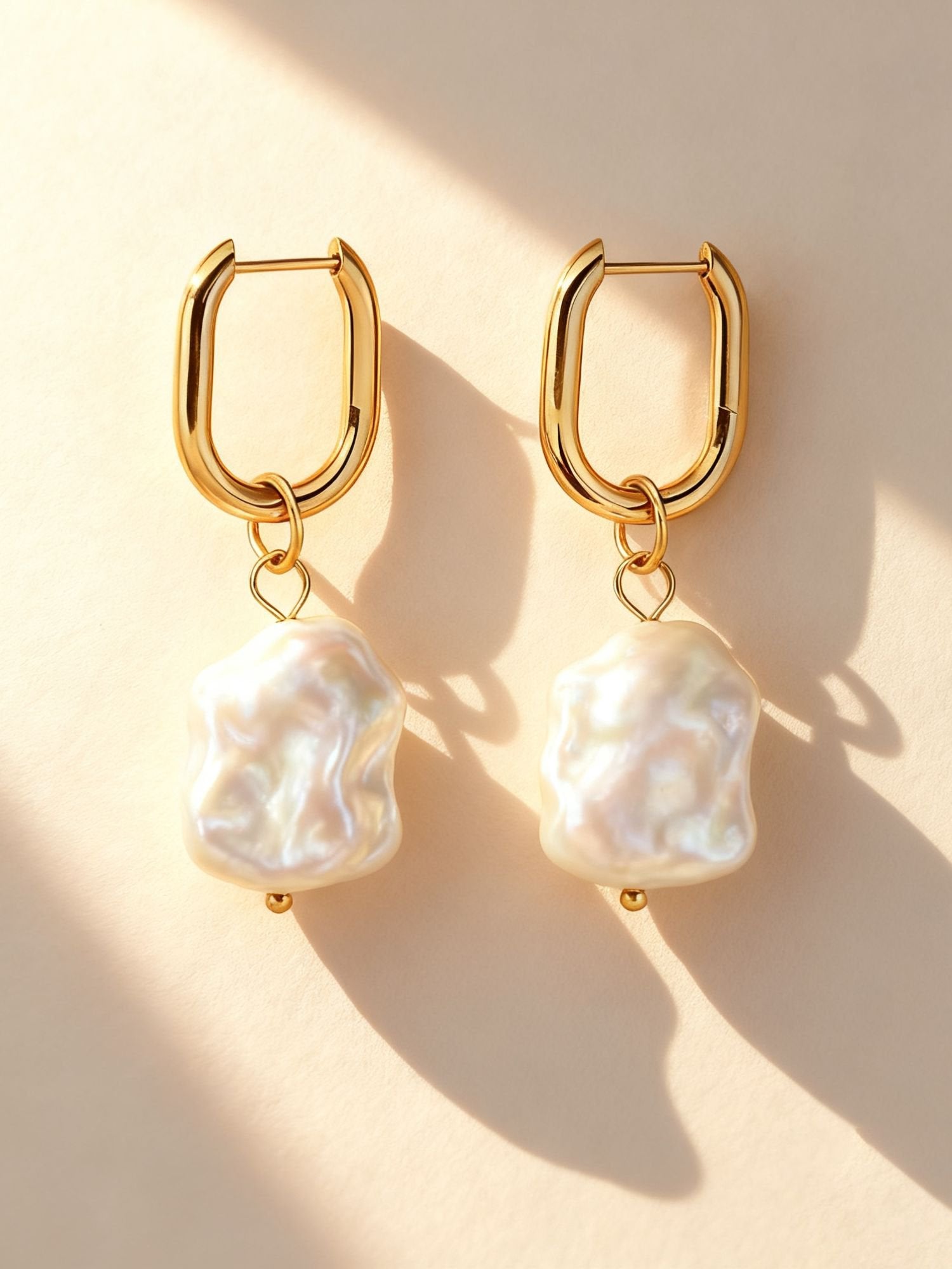 Marea Barock-Perlen Ohrringe – vergoldete U-förmige Creolen mit organischen Perlenanhängern im warmen Licht