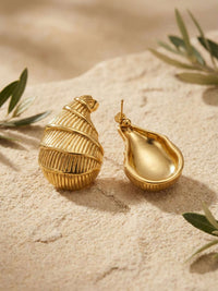 Golden Shell Ohrringe Strand-Atmosphaere – Muschel-Ohrstecker auf Sand mit Olivenzweigen, Vorder- und Rueckseite sichtbar