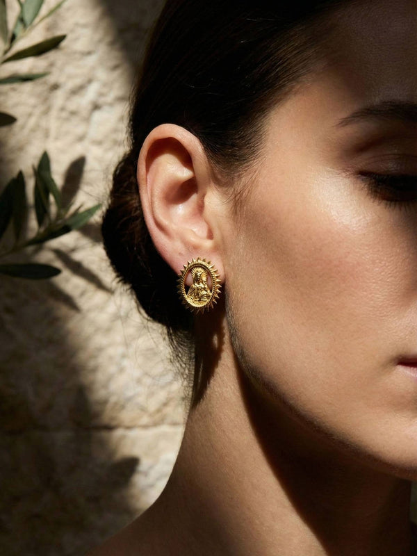 Gloria Ohrringe Ohr-Nahaufnahme – Model mit geschlossenen Augen, goldene Sonnenstrahlen-Ohrringe im Sonnenlicht