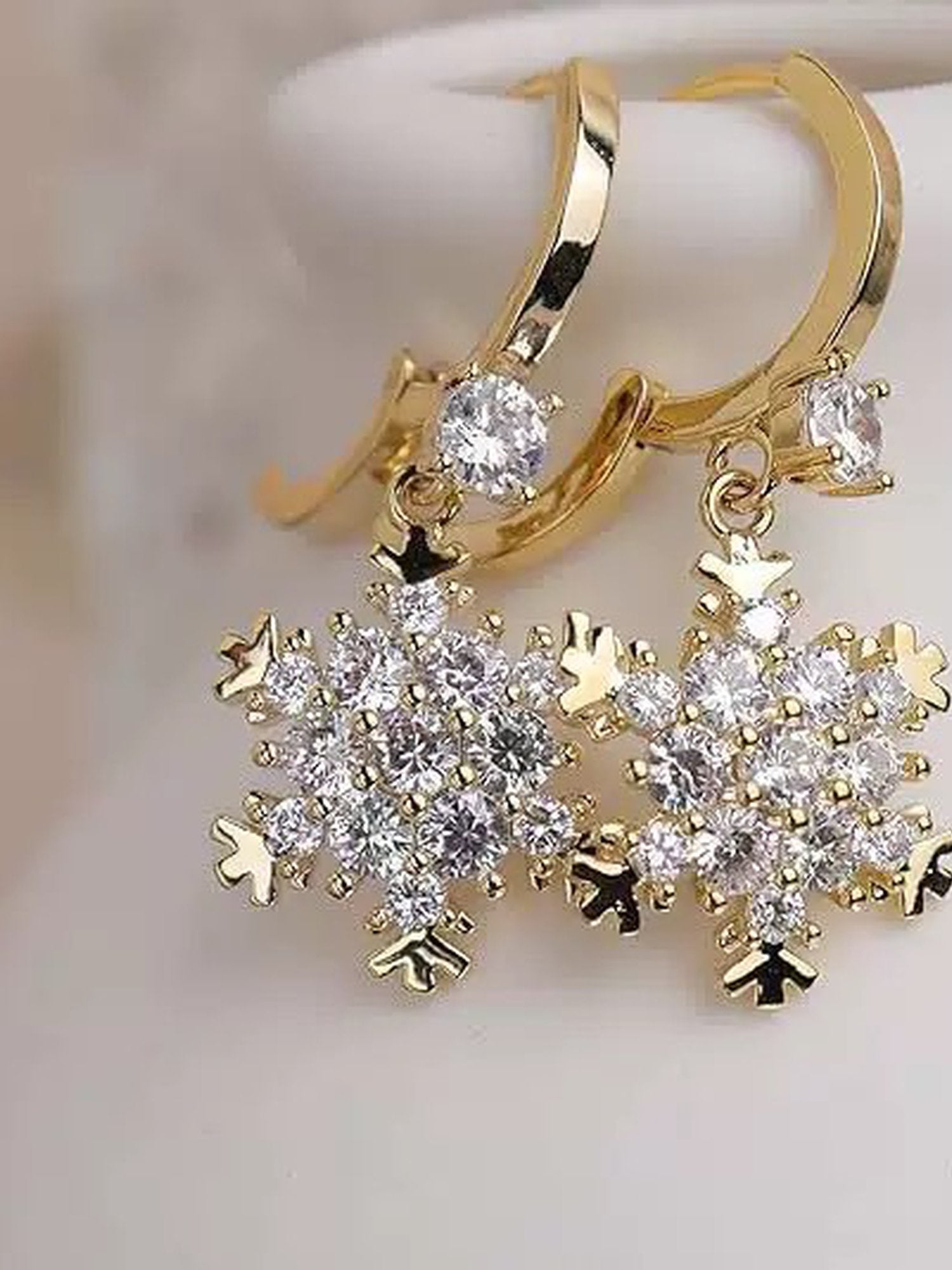 Golden Snowflakes Ohrringe Produktfoto – 18K vergoldete Schneeflocken-Ohrringe mit Zirkonia-Kristallen auf weißem Hintergrund