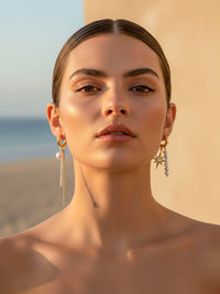 Perla & Stella asymmetrische Ohrringe getragen – goldene Huggie Hoops mit Stern und Perlen an beiden Ohren im Sonnenlicht