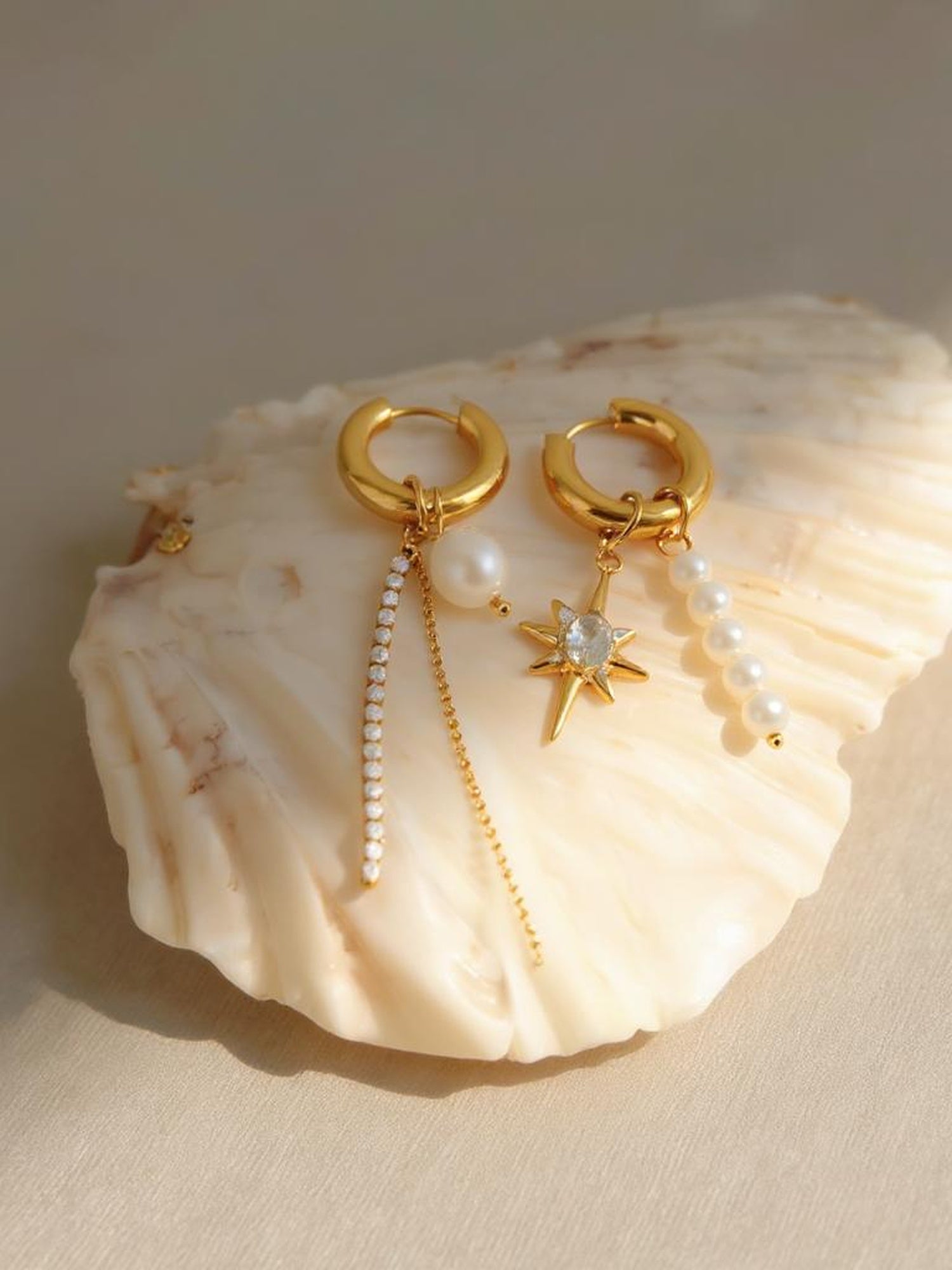 Perla Ohrring Detailaufnahme – goldener Huggie Hoop mit großer Süßwasserperle und Kristallkette