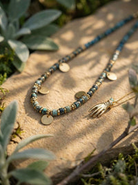 Quiet Protection Schmuck-Set auf Naturstein zwischen Sukkulenten - Türkis-Perlenkette und goldene Hand-Kette im Garten-Ambiente