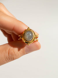 Ring Aurora Filo Detail - vergoldeter Ring mit grauem Labradorit zwischen Fingern - Nahaufnahme