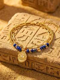 Schutzblick Armband Aegypten Flatlay – Blaues Lapislazuli-Armband mit Nazar-Anhaenger auf Hieroglyphen-Stein Sand-Atmosphaere