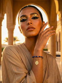 Schutzblick Armband getragen Orient – Lapislazuli-Perlenarmband mit Schutzauge an Frau vor orientalischer Architektur goldenes Licht