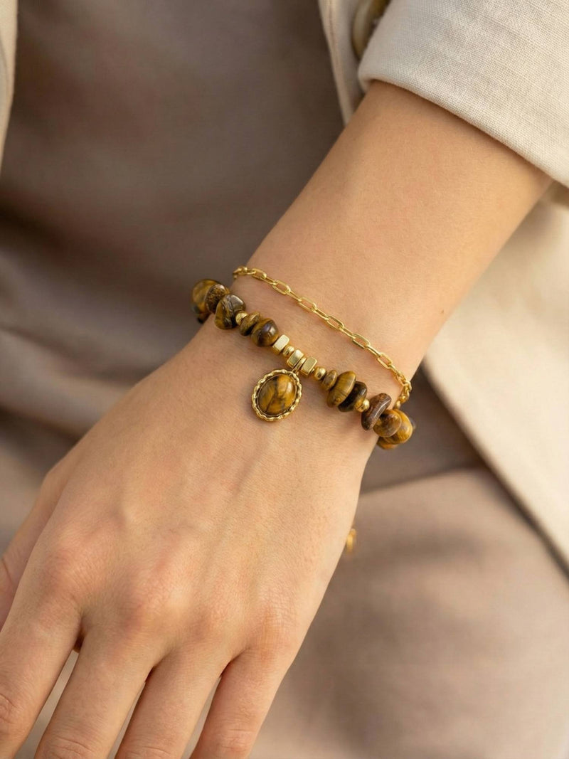 Stein und Glanz Armband Hand Beige – Tigerauge-Steinarmband getragen beige Stoffhintergrund warme Atmosphaere Boho-Schmuck