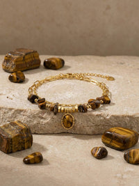Stein und Glanz Armband Stein Flatlay – Tigerauge-Armband auf Marmor mit losen Tigerauge-Steinen Erdtoene natuerliches Licht