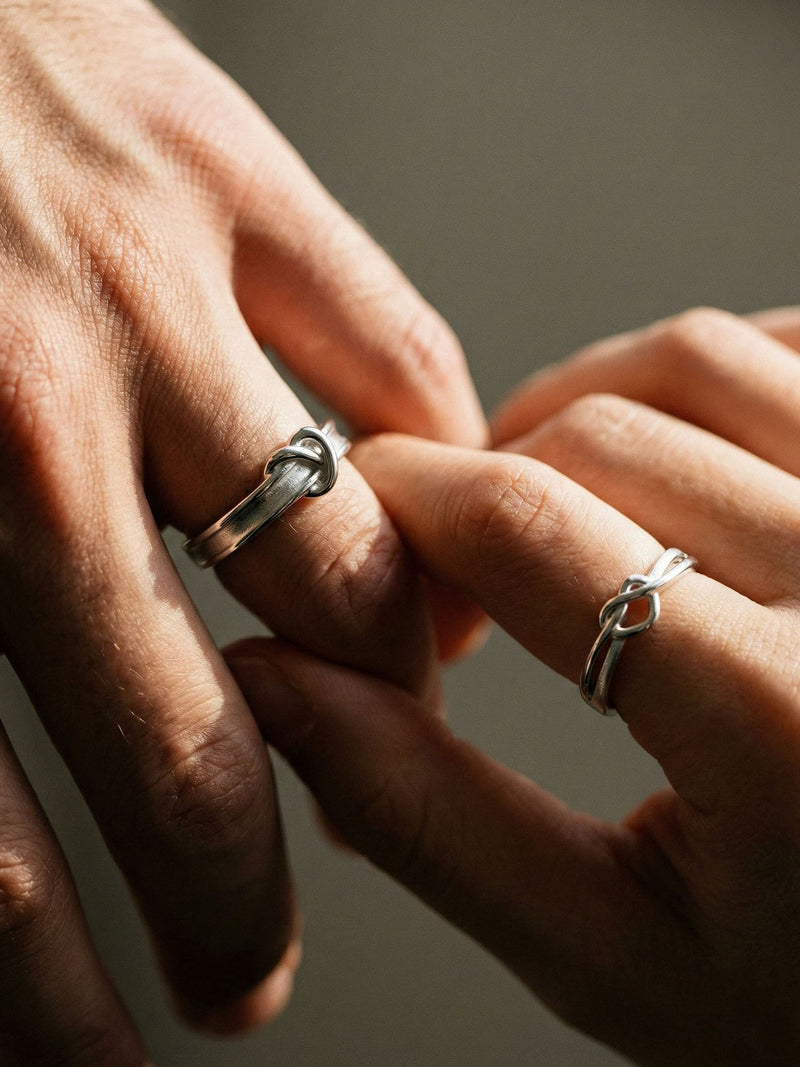 Paar traegt Still Connected Partnerringe - 925 Silber Knotenringe, romantische Handberuehrung