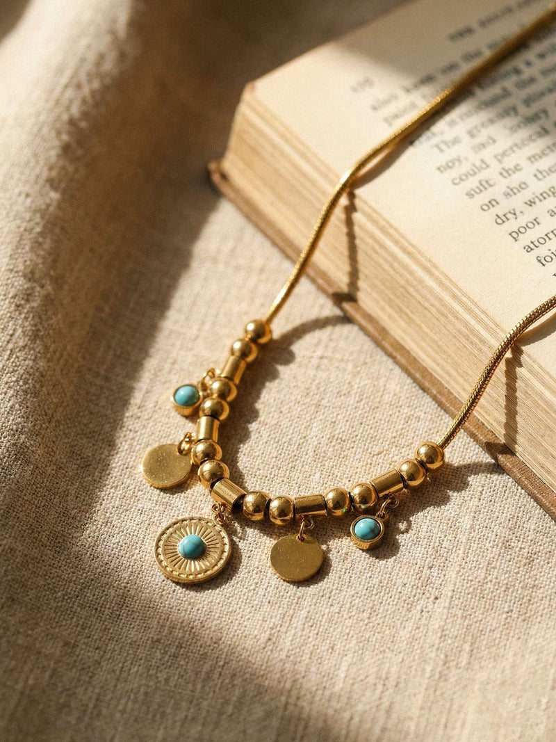 Goldene Tuerkis-Kette auf altem Buch im warmen Sonnenlicht - Boho Schmuck Lifestyle Foto mit Leinen-Stoff