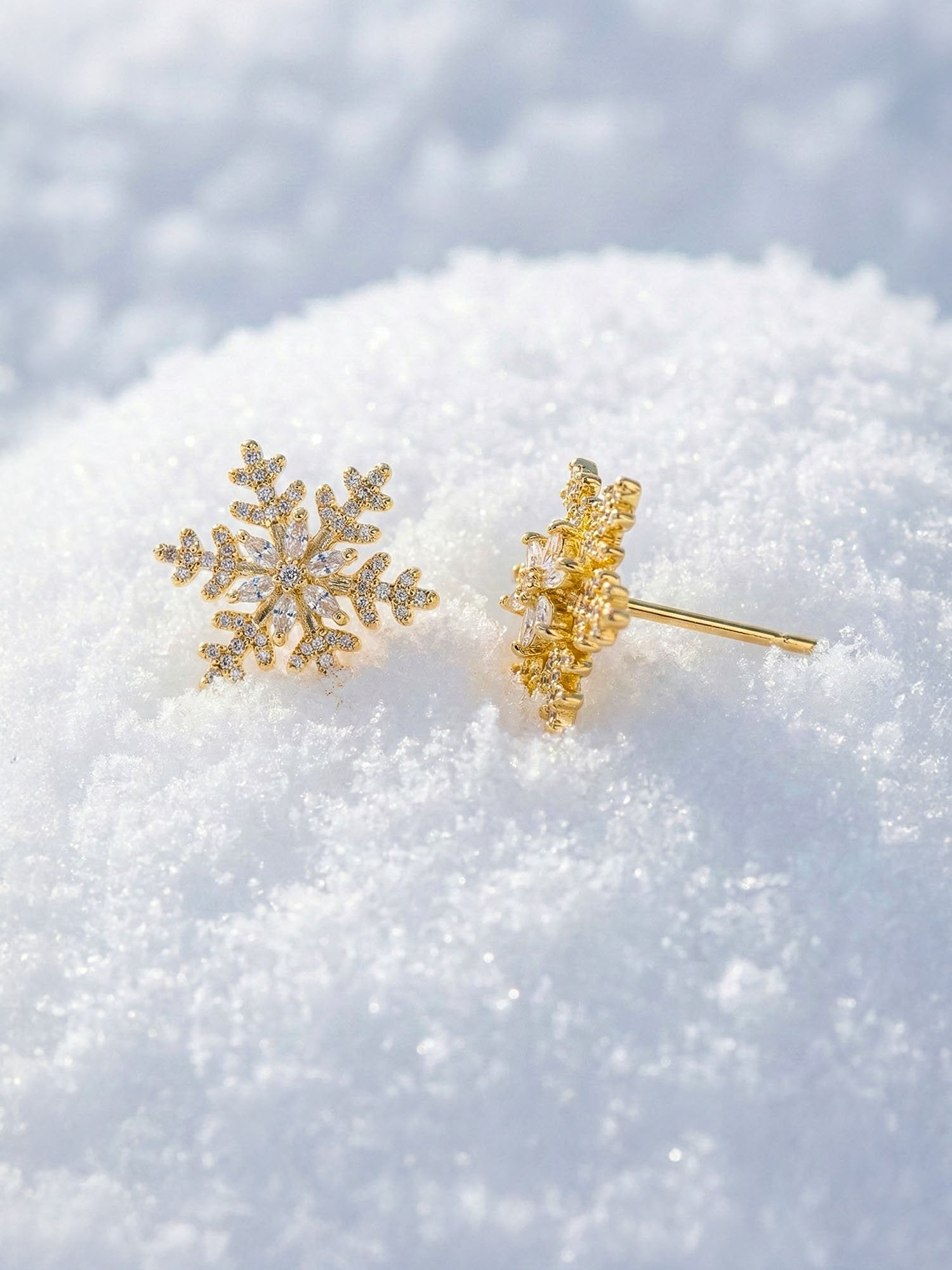 Winterlicht Schneeflocken-Ohrstecker im Schnee – goldene Schneeflocken-Ohrringe auf Schnee Winter-Lifestyle-Fotografie