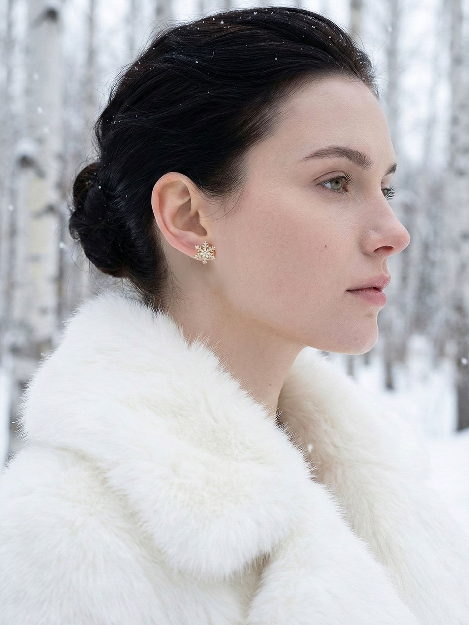 Winterlicht Schneeflocken-Ohrstecker getragen – Frau trägt vergoldete Schneeflocken-Ohrringe im Winter mit weißem Pelzmantel