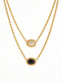 Yin Yang Glow Kette Produktfoto – vergoldete Doppelkette mit hellem und dunklem Katzenauge-Stein auf weissem Hintergrund